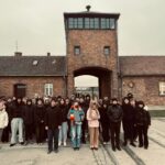 młodzież na tle bramy obozu Birkenau